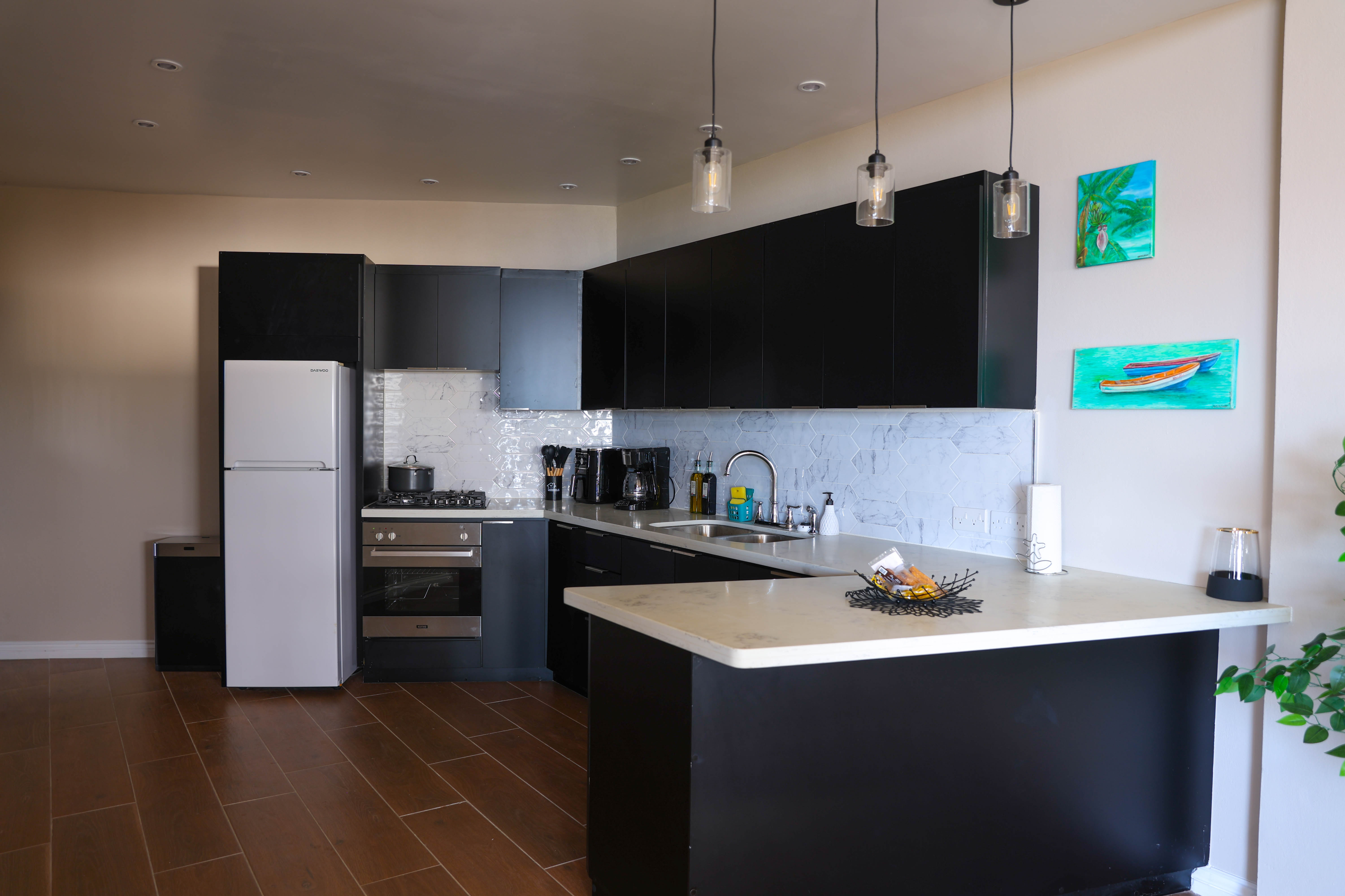 Fully equipped open-plan kitchen at Serene Sunset Escapes Saint Lucia — black matte cabinets and marble countertops
