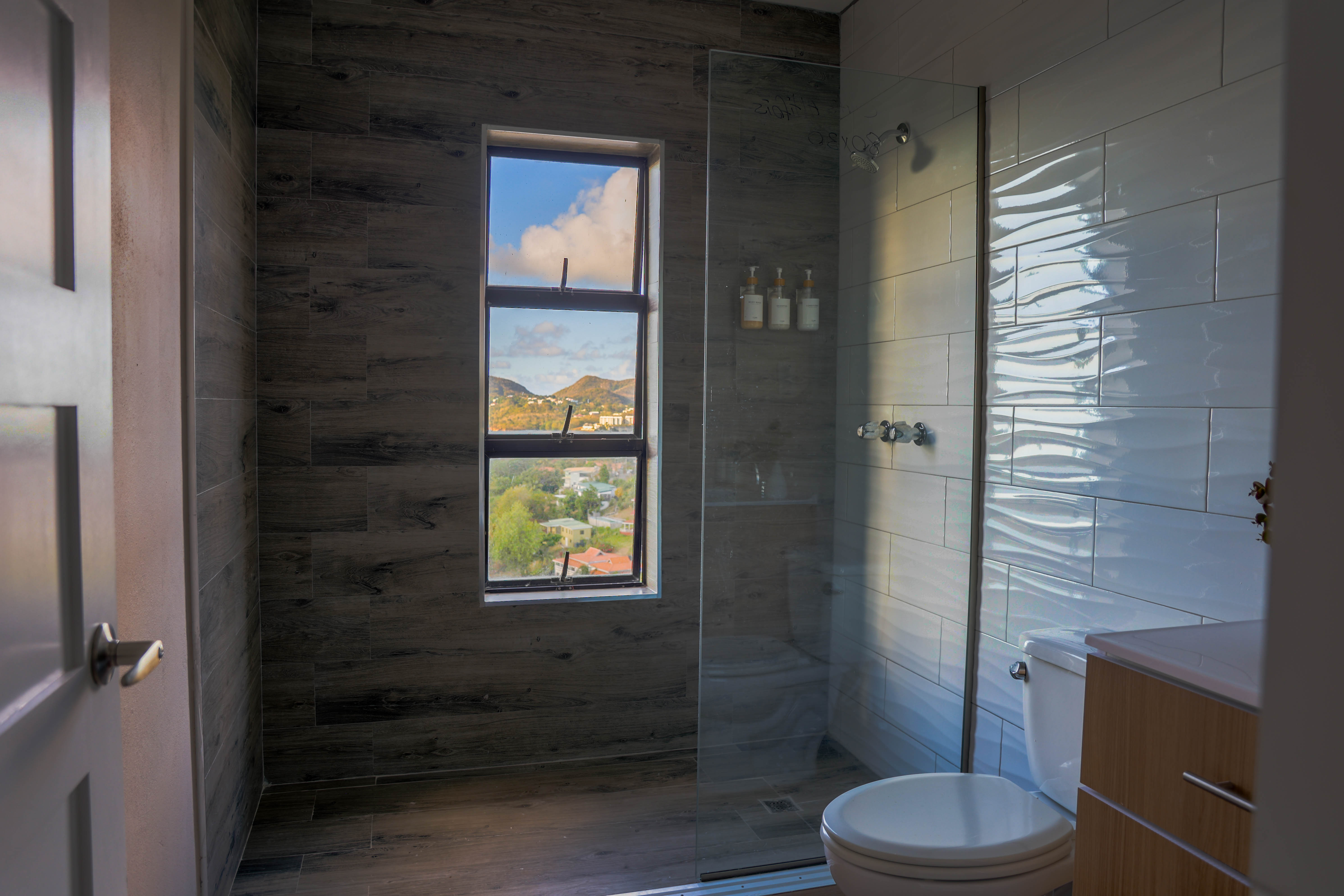Luxury en-suite bathroom Serene Sunset Escapes Saint Lucia — rain shower with panoramic hill view